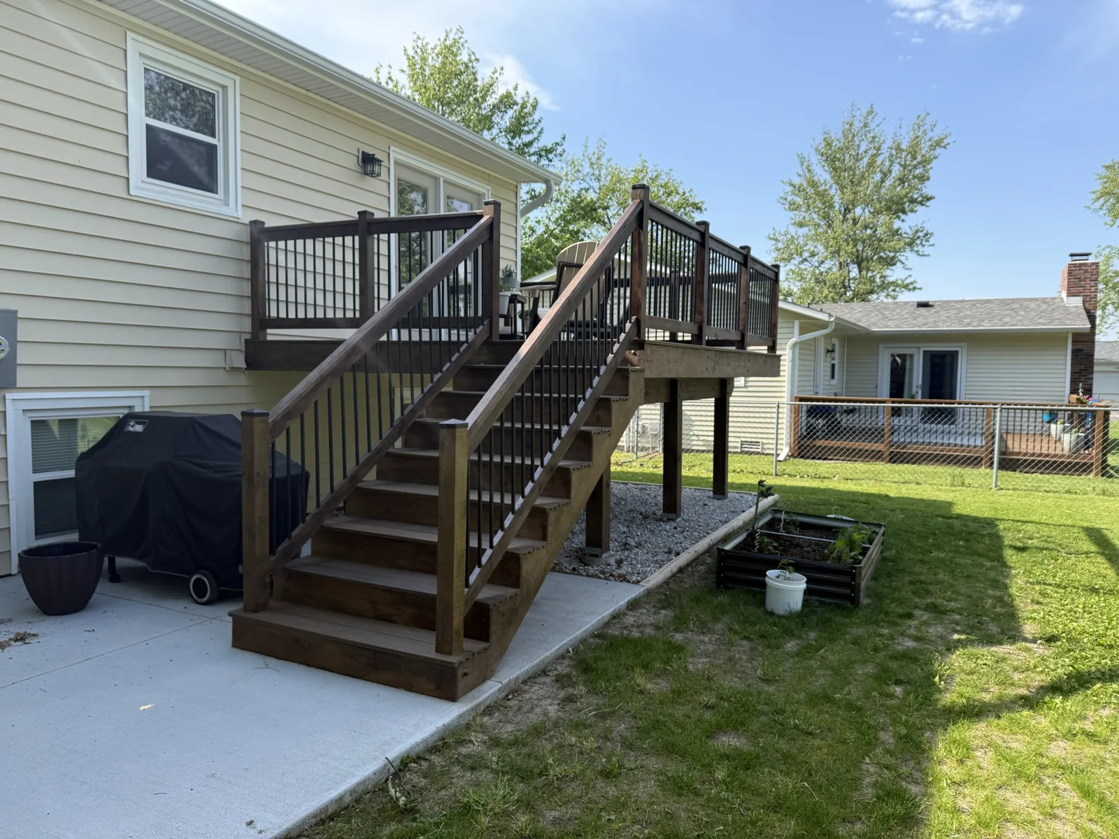 Completed backyard deck with stair run and black metal balusters
